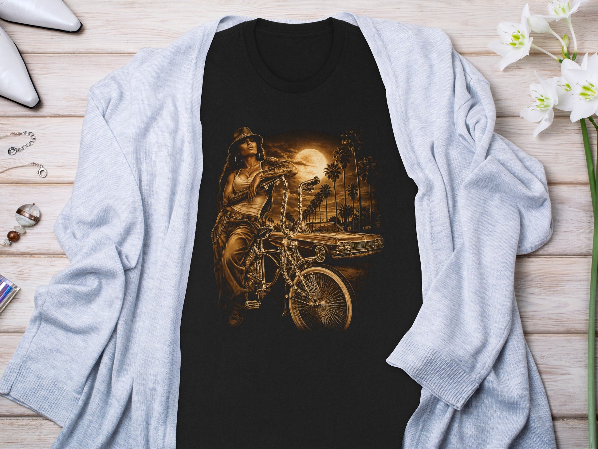 Black t-shirt with graphic of woman on bicycle and classic car at sunset.