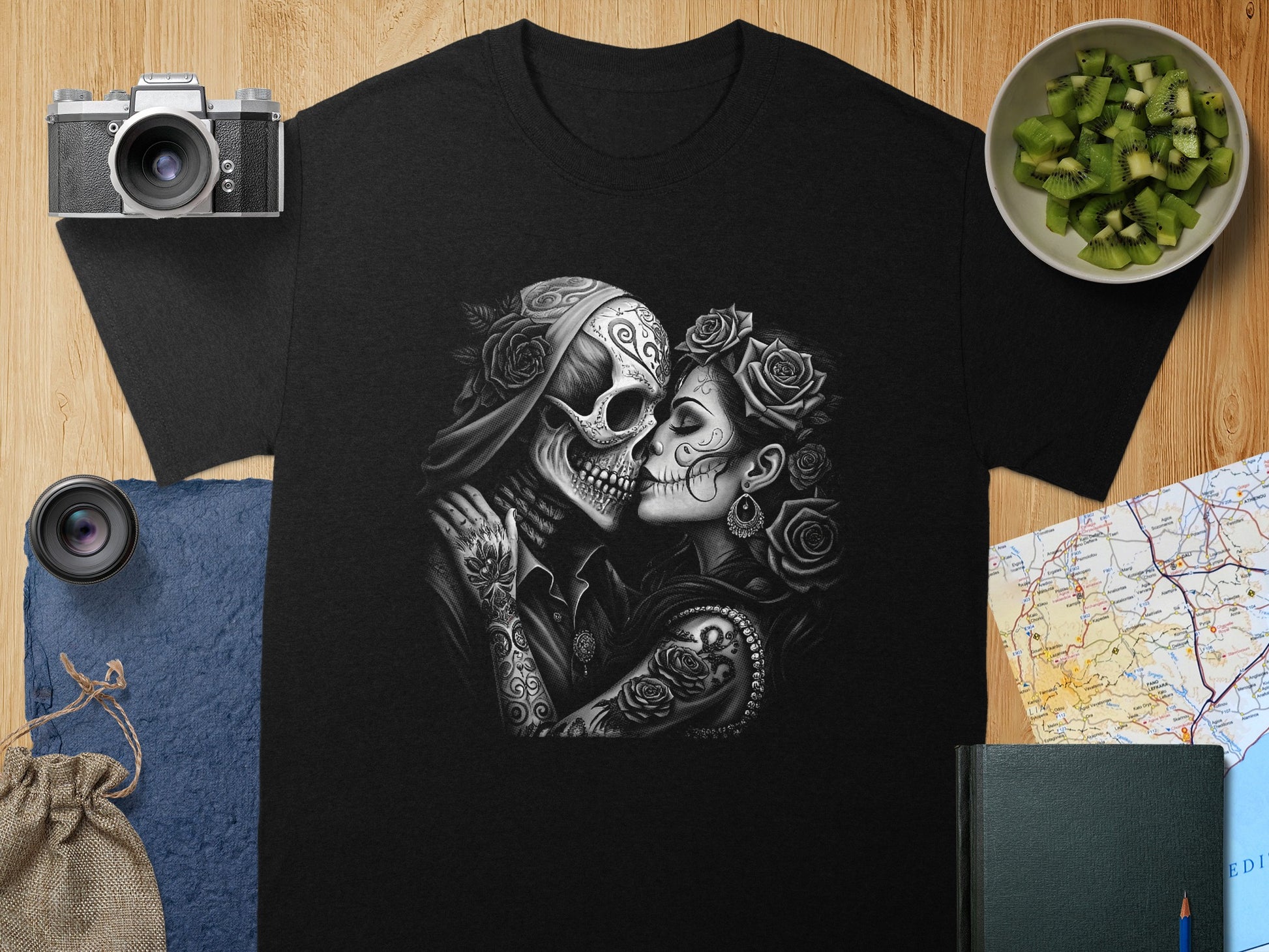 Tattooed skulls in embrace, with roses and makeup, on a black t-shirt.
