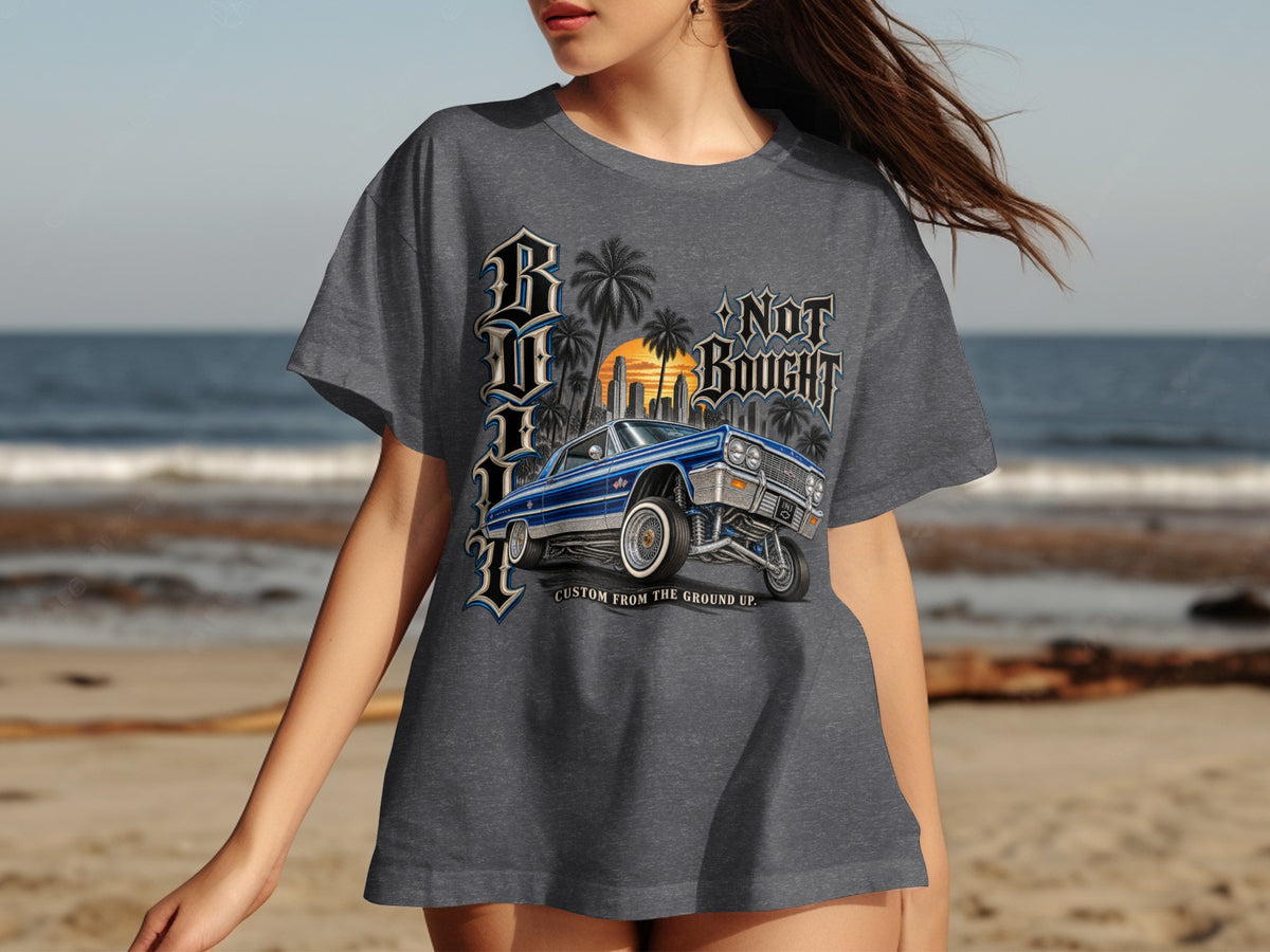 Dark gray t-shirt with "BLU" text, a blue classic car, and "NOT BOUGHT CUSTOM FROM THE GROUND UP." text.