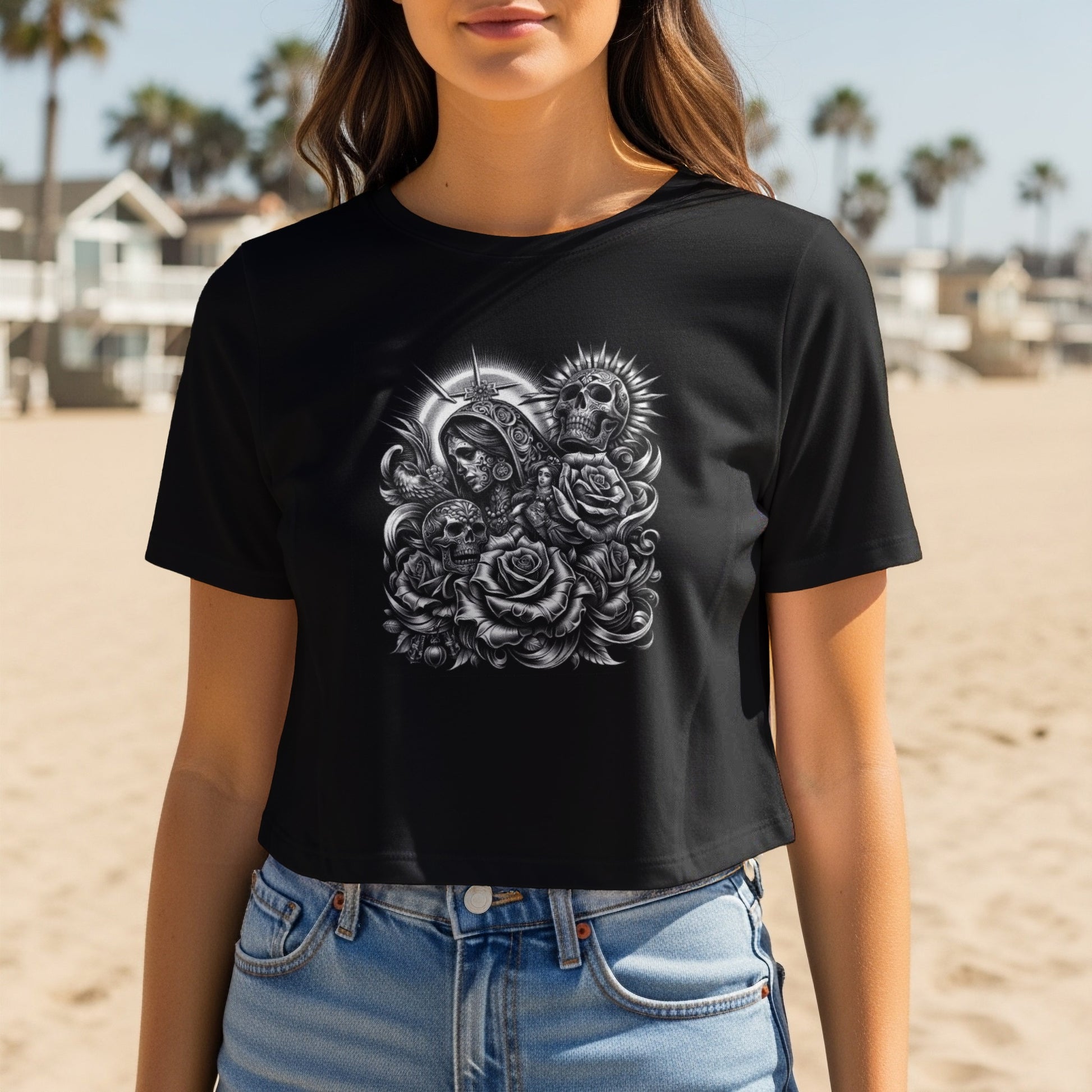 Black crop top with skull and rose graphic on a beach.