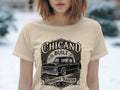 Chicano Built lowriding tradition graphic with black truck and roses on beige t-shirt.