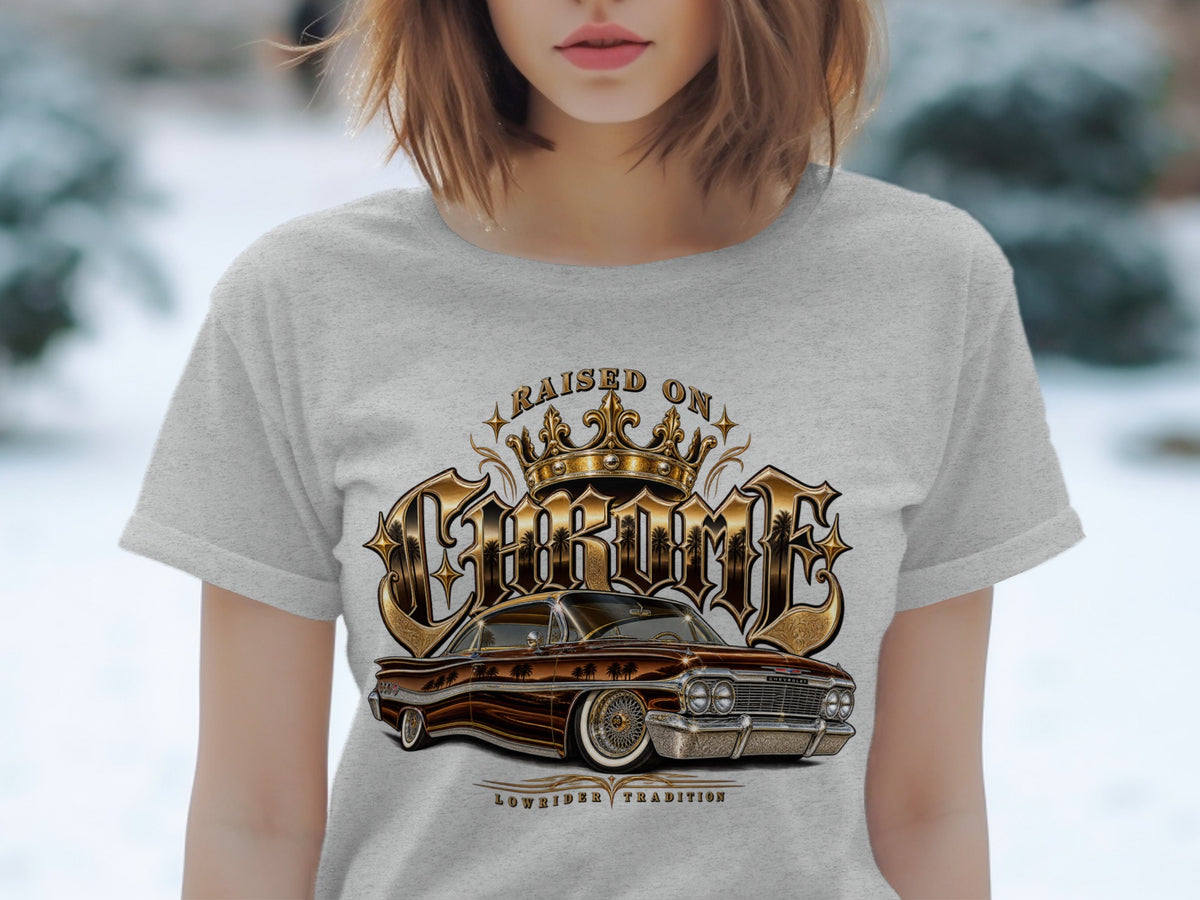 T-shirt graphic with vintage lowrider car, crown, and text "RAISED ON CHROME LOWRIDER TRADITION".