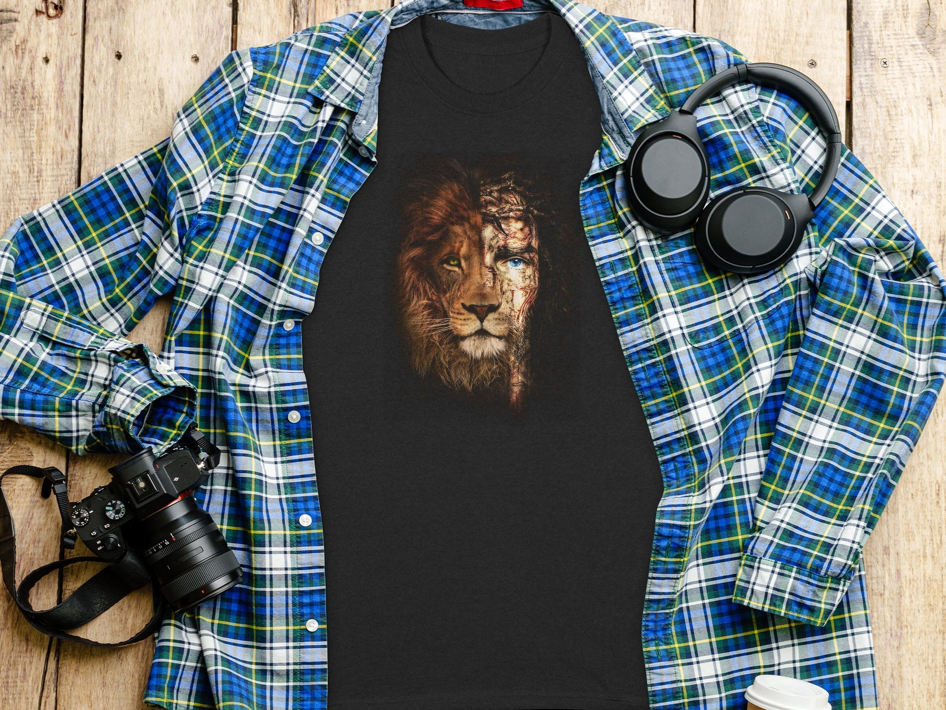 Black t-shirt with lion's face, half human, half divine, on wooden background.