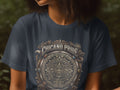 Dark t-shirt with circular Chicano Pride emblem featuring eagle and serpent.