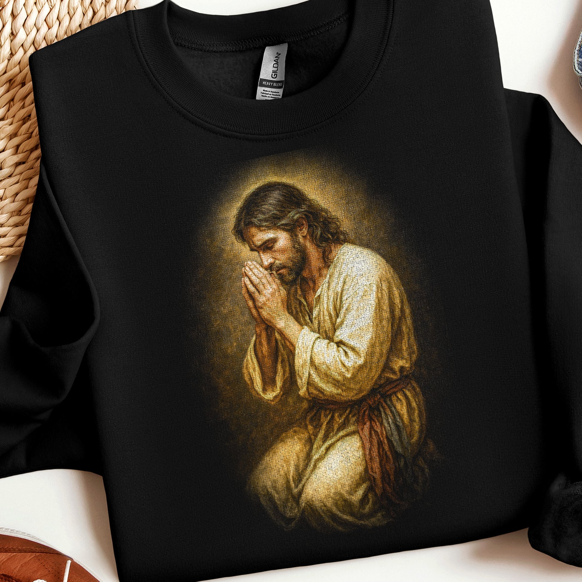Jesus praying, depicted in a painted style on a black sweatshirt.