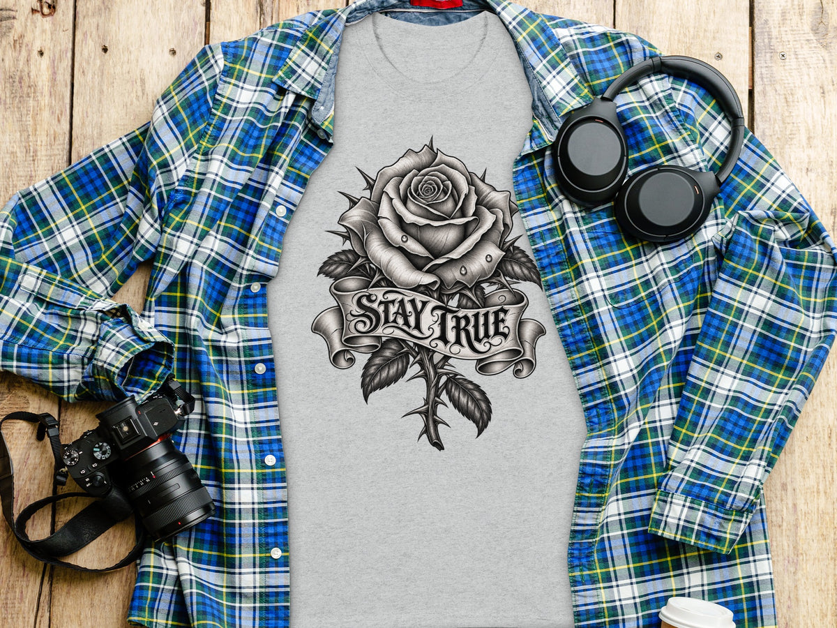 Gray t-shirt with rose graphic and "Stay True" text, laid with open plaid shirt.