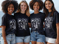 Four smiling young women wear black t-shirts with a circular graphic and 
