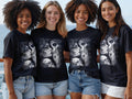 Four women wear t-shirts featuring Day of the Dead skull designs.