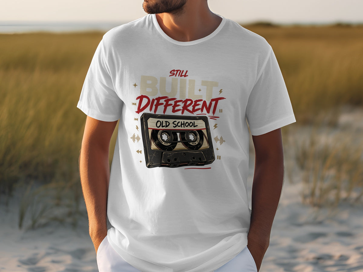 White t-shirt with text "Still Built Different" and a cassette tape graphic.