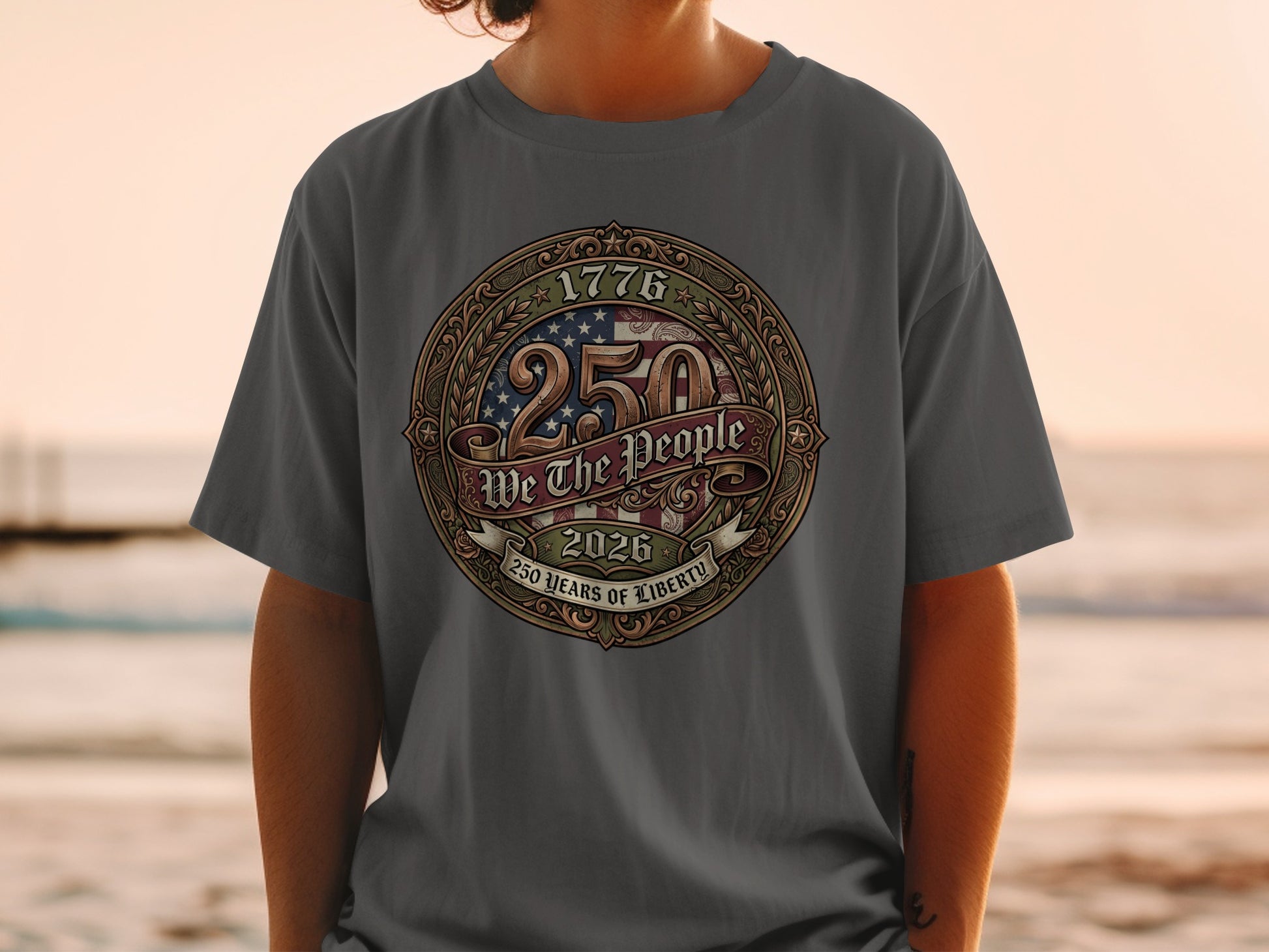 Gray t-shirt featuring a patriotic circular emblem with "1776 250 YEARS OF LIBERTY 2026" and "WE THE PEOPLE".