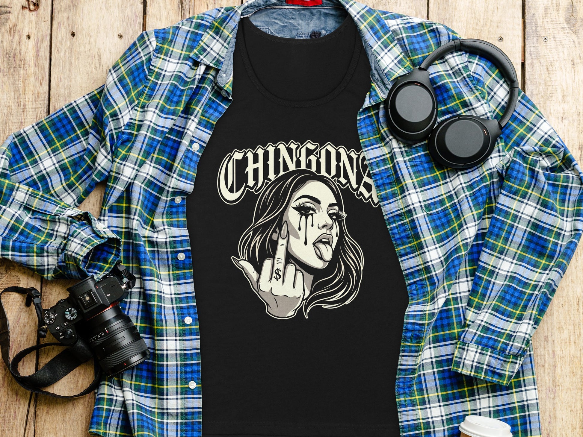 Black t-shirt with woman graphic and "CHINGONA" text, laid on flannel.