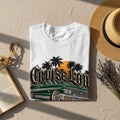 White t-shirt with green lowrider, palm trees, and sunset graphic.