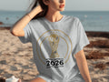 Gray t-shirt with North America 2026 FIFA World Cup logo on beach.