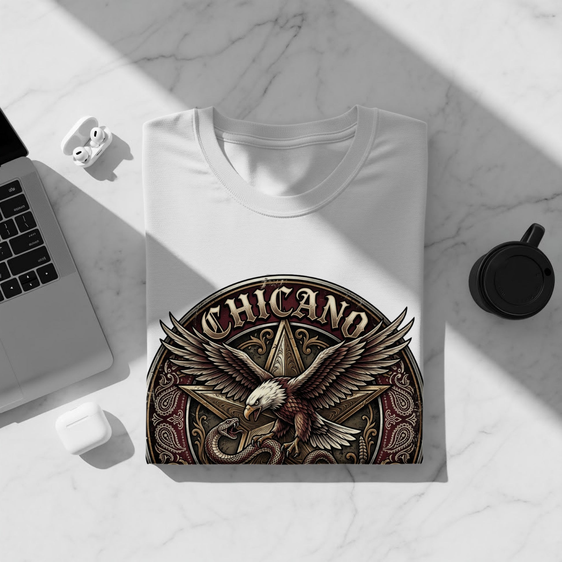 White t-shirt with Chicano eagle and snake graphic on a white surface.