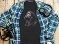 T-shirt with Jesus Christ graphic, headphones, and camera on a wooden surface.