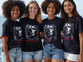 Four smiling women wear matching t-shirts with a skull and floral design.
