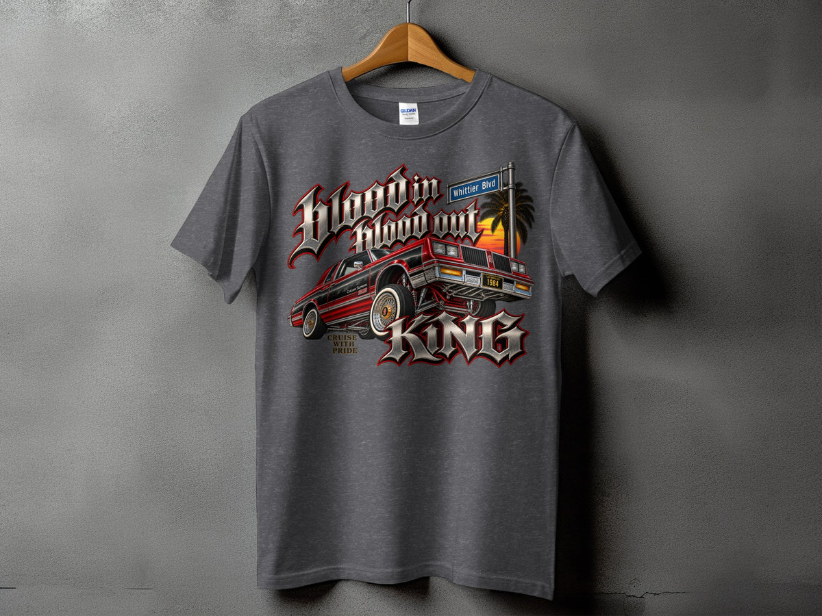 T-shirt graphic with a lowrider car, palm tree, sunset, and text "blood in blood out KING".