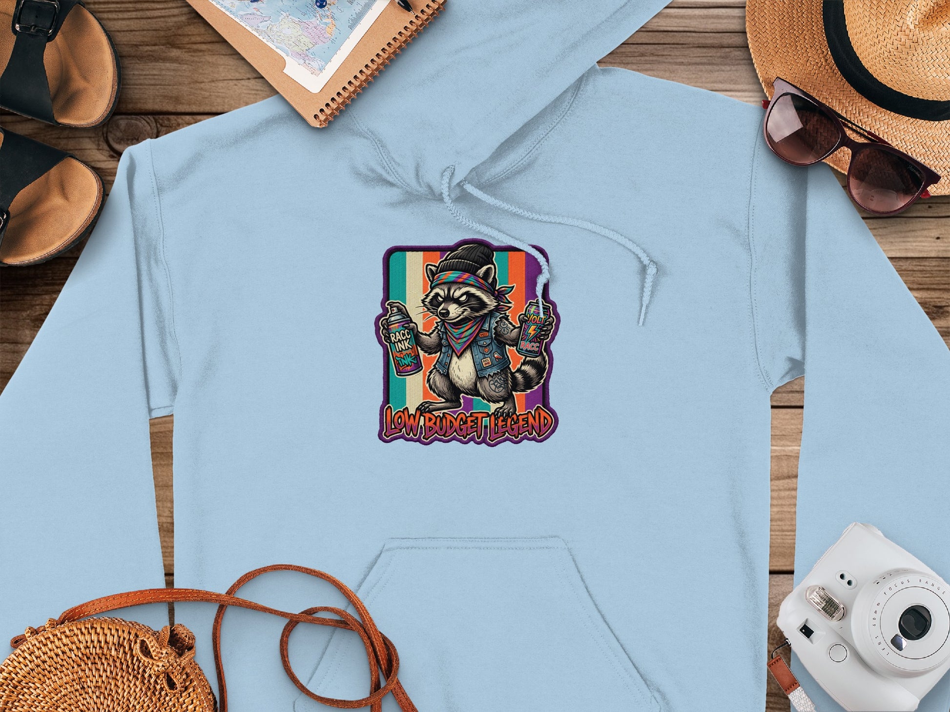 Light blue hoodie with cartoon raccoon holding paint cans, "LOW BUDGET LEGEND" text.