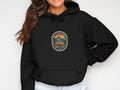 Black hoodie with circular patch design featuring mountains, van, and text.