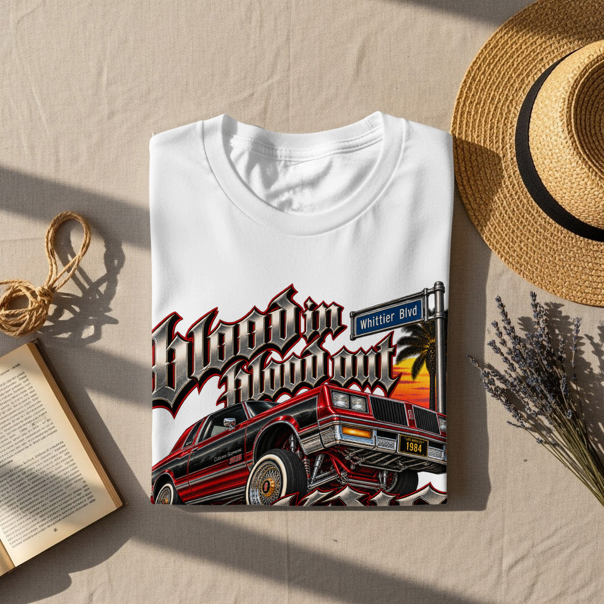 White t-shirt with "Hoodin Blowout" graphic featuring a red 1984 Cutlass Supreme and Whittier Blvd sign.