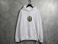 Grey hoodie with circular embroidered nature scene: mountains, trees, sun.