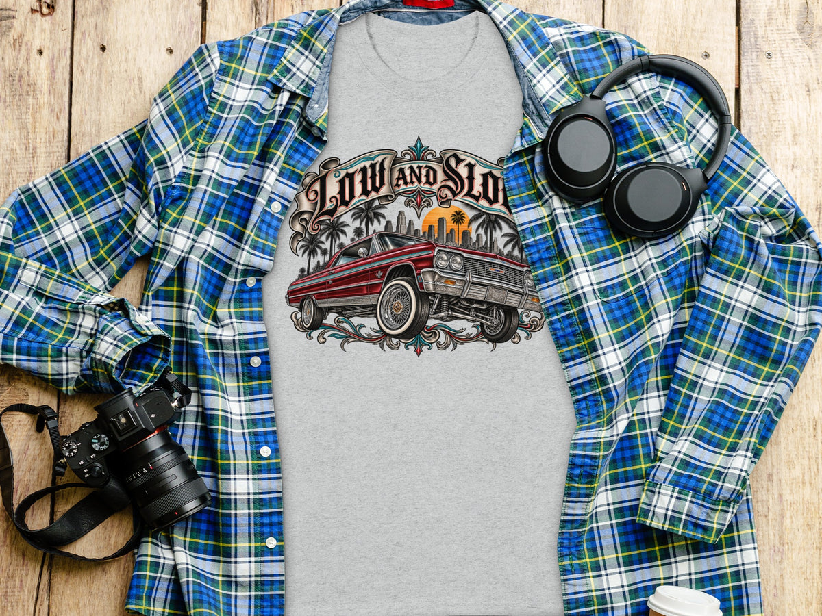 Grey t-shirt with "Low and Slo" text and lowrider car graphic, laid flat with open plaid shirt.