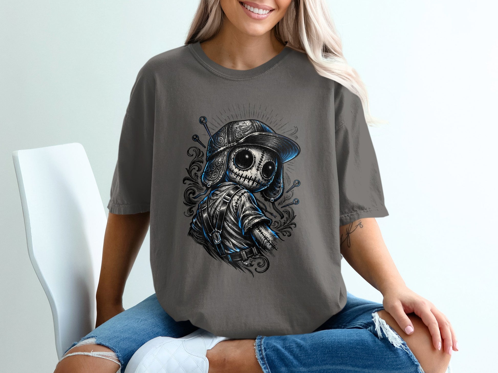 Dark grey t-shirt with a stylized doll wearing a baseball cap and backpack.