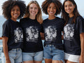 Four women wearing black t-shirts with a graphic of a woman and city skyline.