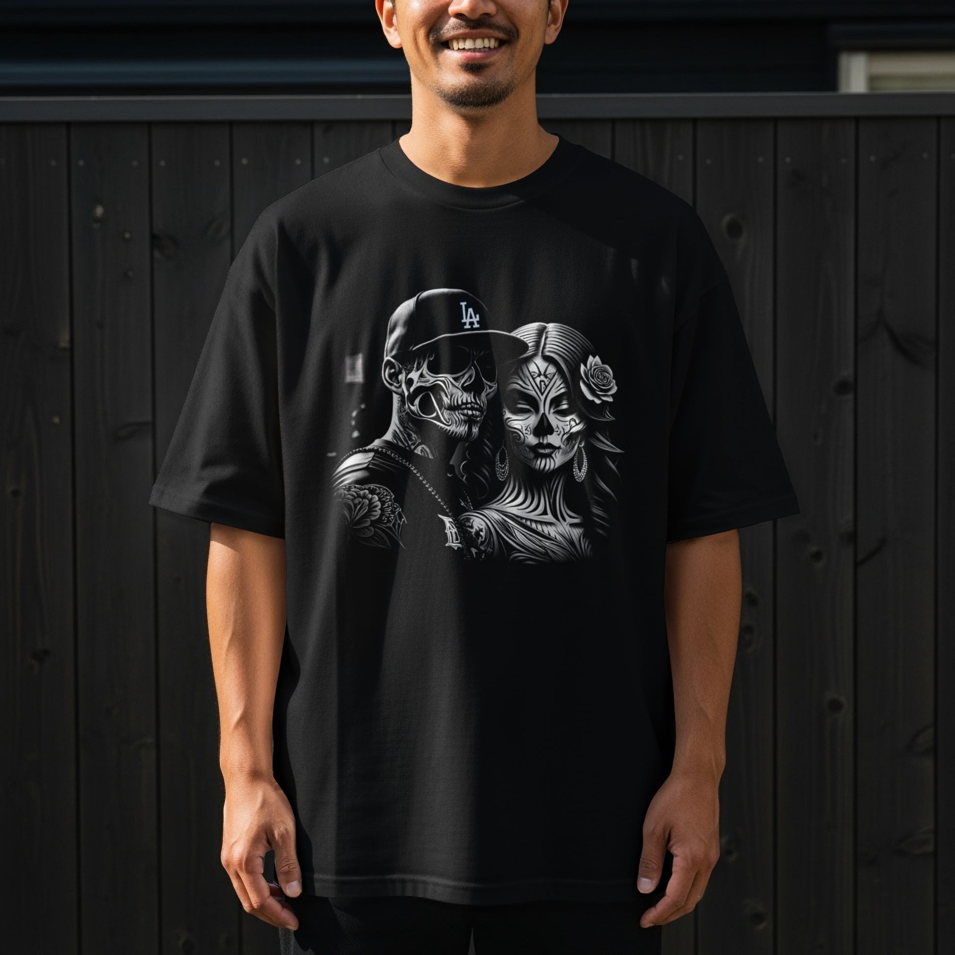Black t-shirt featuring a Day of the Dead couple illustration with "LA" on the hat.