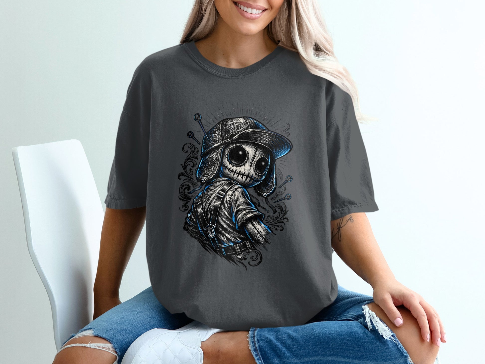 Dark grey t-shirt with graphic of a stylized doll wearing a baseball cap.