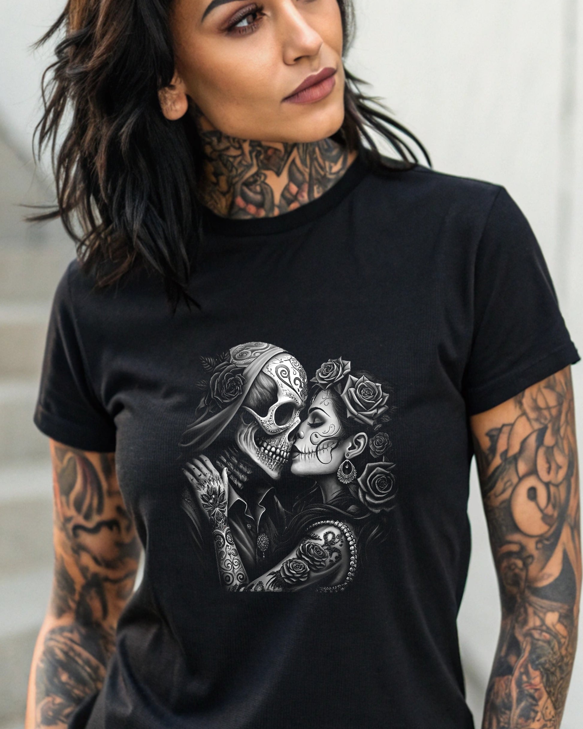 Tattooed couple of skulls in embrace, adorned with roses, on a black t-shirt.