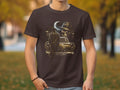Dark t-shirt with graphic of a skull in a fedora and plaid shirt, standing by a vintage car.