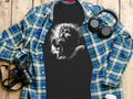 Black t-shirt with Jesus Christ on the cross graphic, laid flat with headphones and camera.