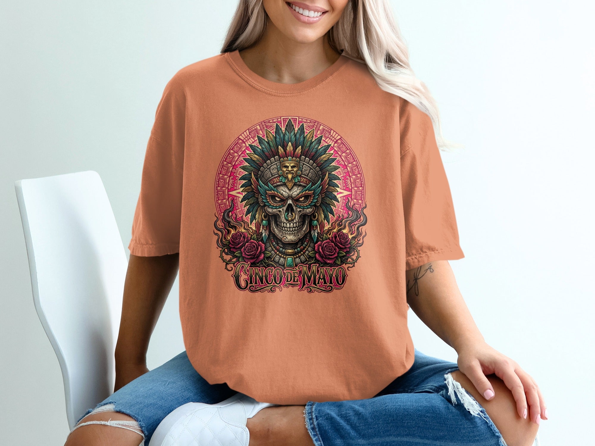 Peach t-shirt featuring a skull with a headdress and roses, "Cinco de Mayo" text.