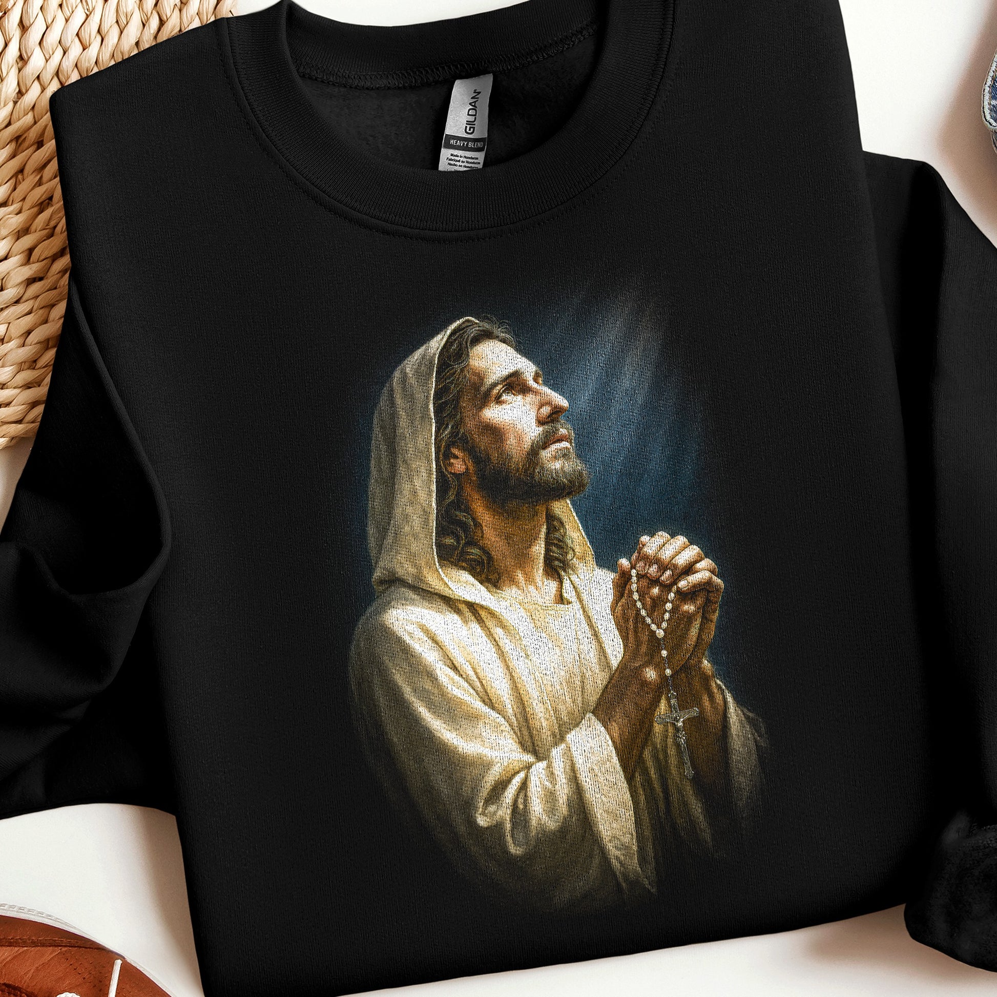 Black sweatshirt with depiction of Jesus praying with rosary beads.