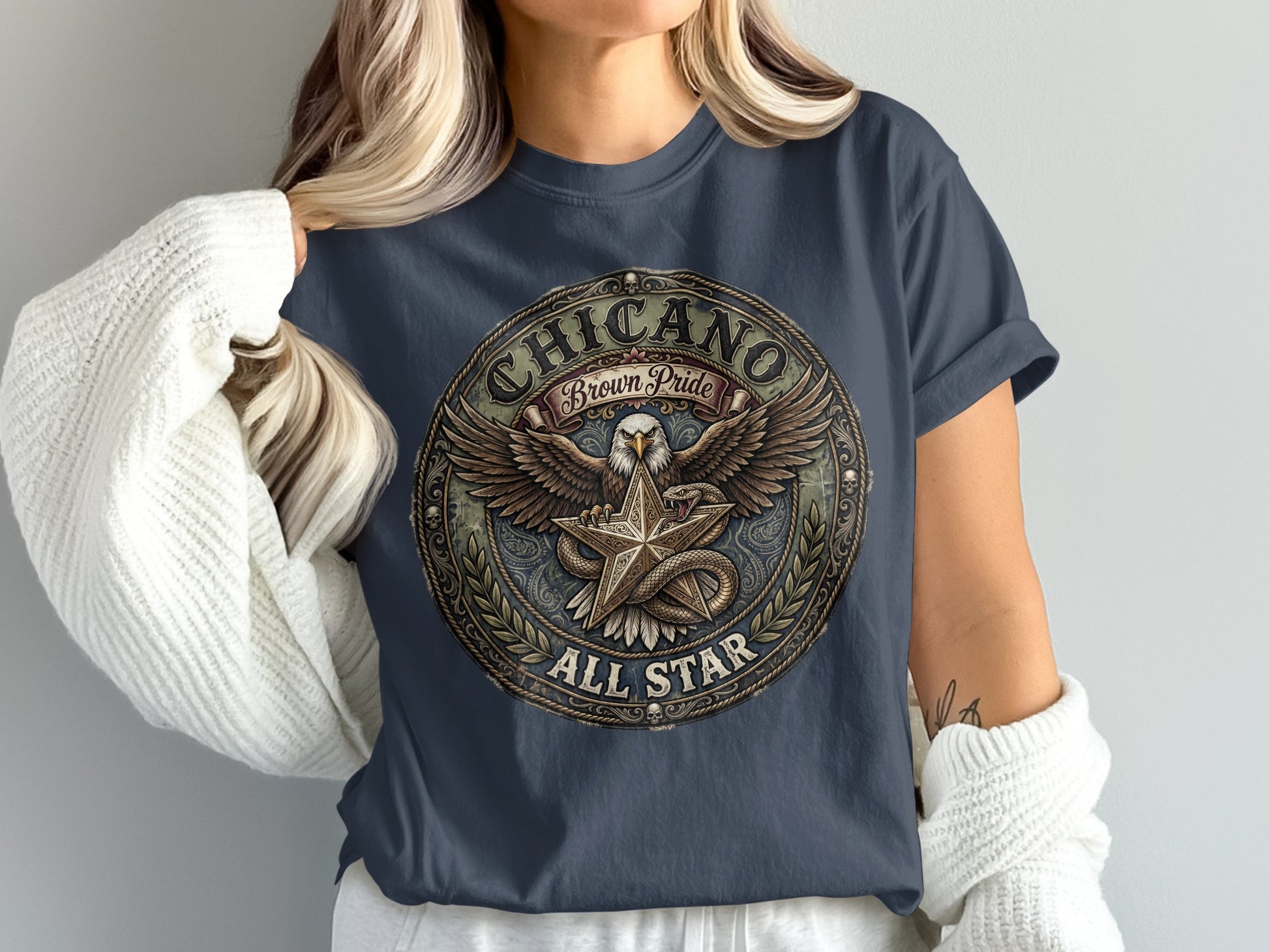 Circular Chicano Brown Pride graphic with eagle, star, and snake on navy t-shirt.