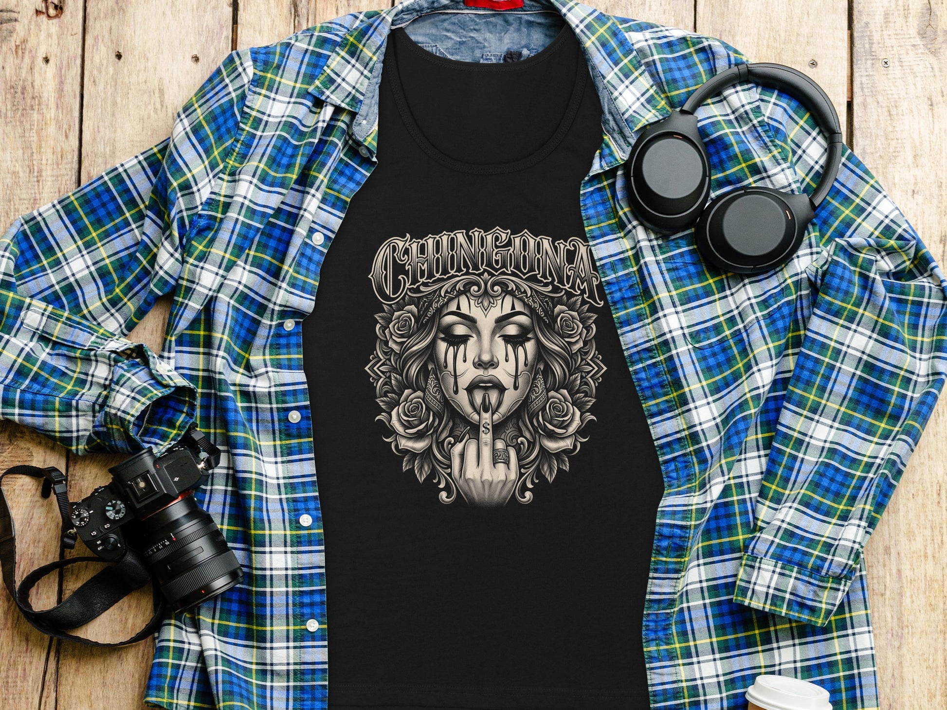 Black t-shirt with "CHINGONA" text and a skull graphic, laid on a flannel shirt.