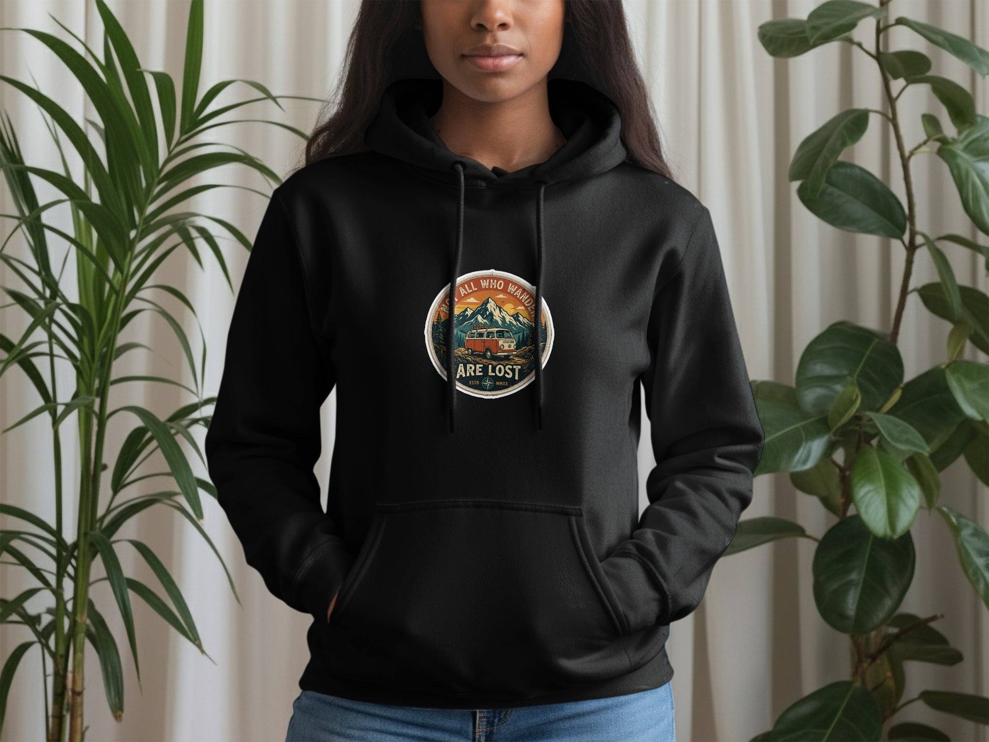 Black hoodie with circular nature graphic featuring a camper van and mountains, text reads "Not all who wander are lost".