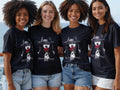 Four women in black t-shirts with a woman and rose graphic, 