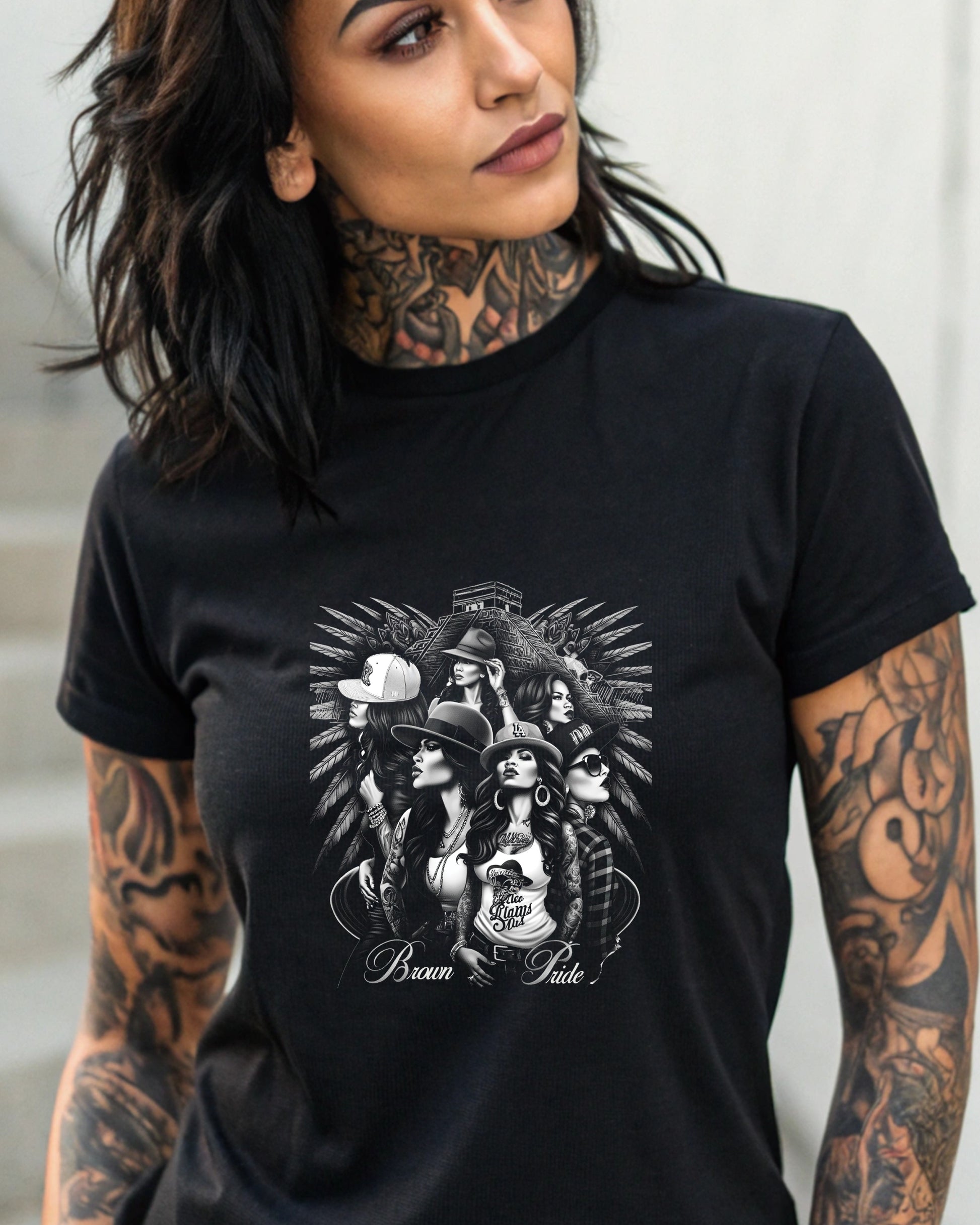 Tattooed woman wearing a black t-shirt with a Brown Pride graphic.