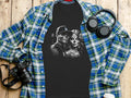 Black t-shirt with skull couple graphic, folded over plaid shirt and headphones.