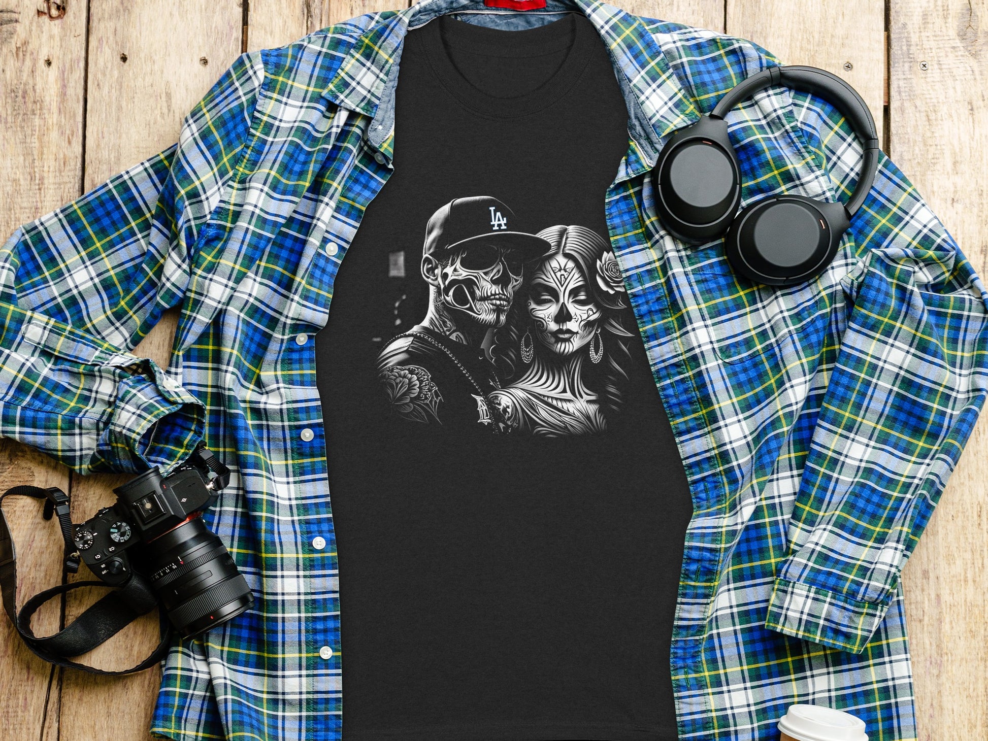 Black t-shirt with skull couple graphic, folded over plaid shirt and headphones.