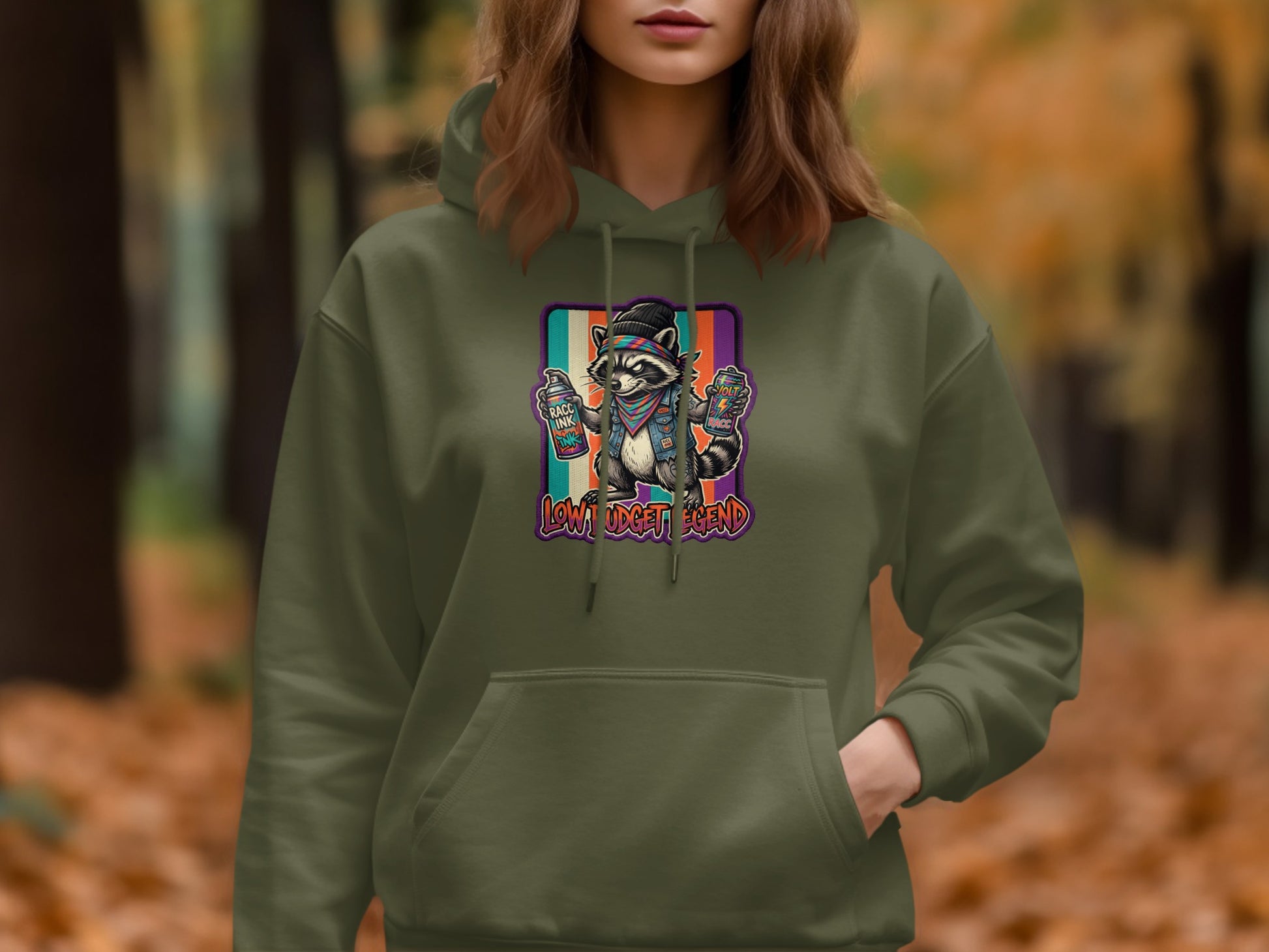 Green hoodie with a raccoon spraying colorful graffiti art, "Low Budget Legend" text.