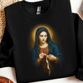 Madonna with halo stitching a ribbon, depicted on a black sweatshirt.