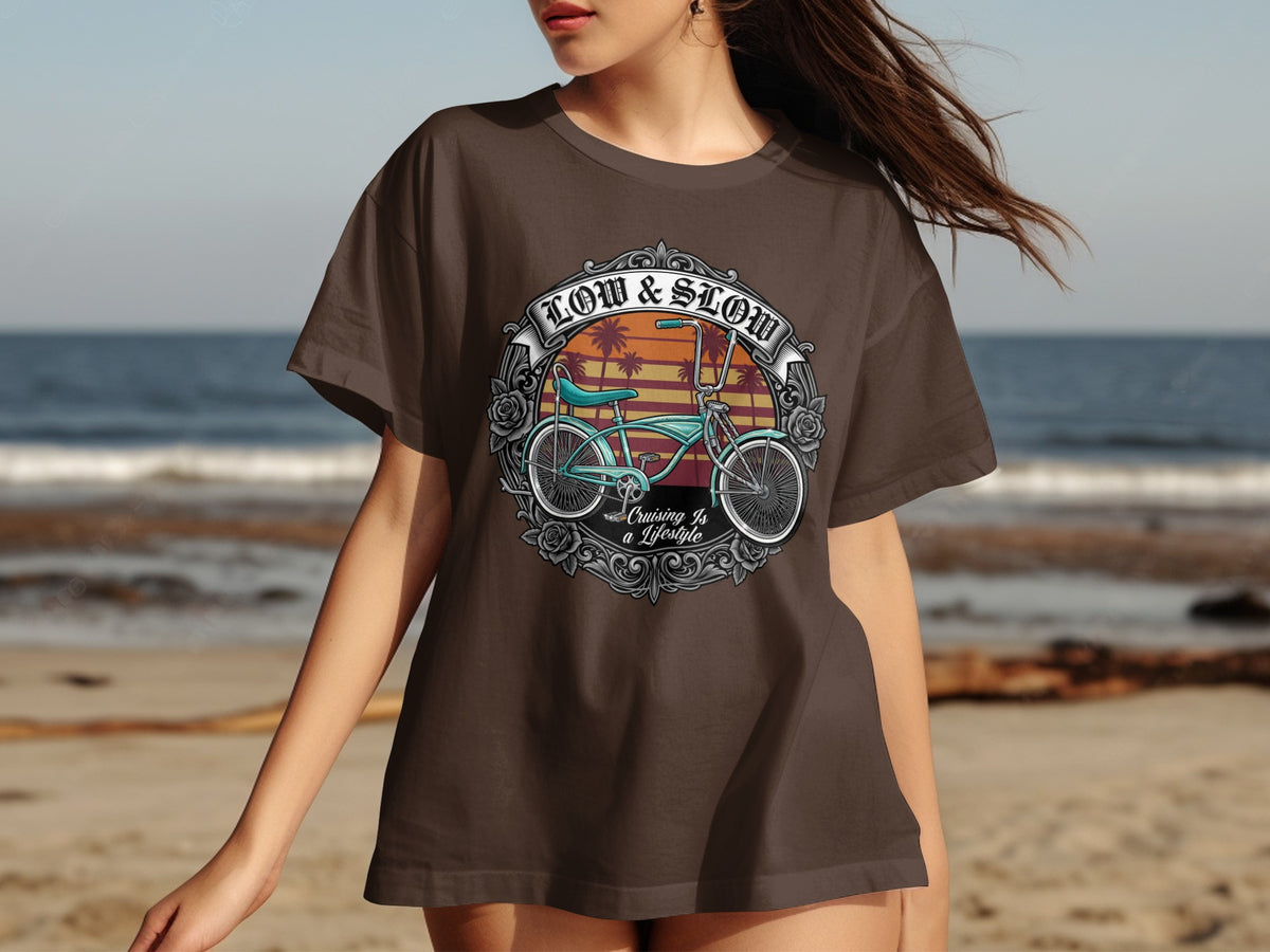 Brown t-shirt with a circular graphic featuring a vintage bicycle, palm trees, and text "Low & Slow Cruising Is a Lifestyle".