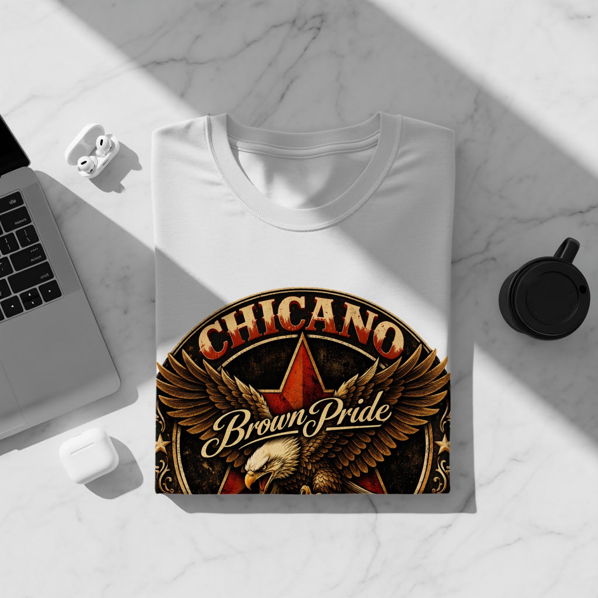 White t-shirt with Chicano Brown Pride eagle logo on a flat lay surface.