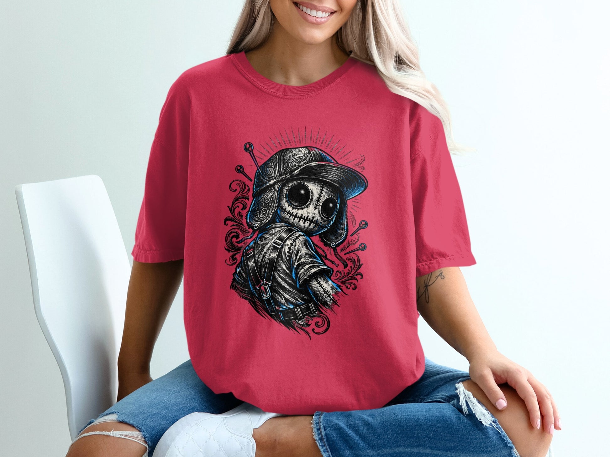 Woman wearing a red t-shirt with a skull graphic, jeans, sitting on a chair.